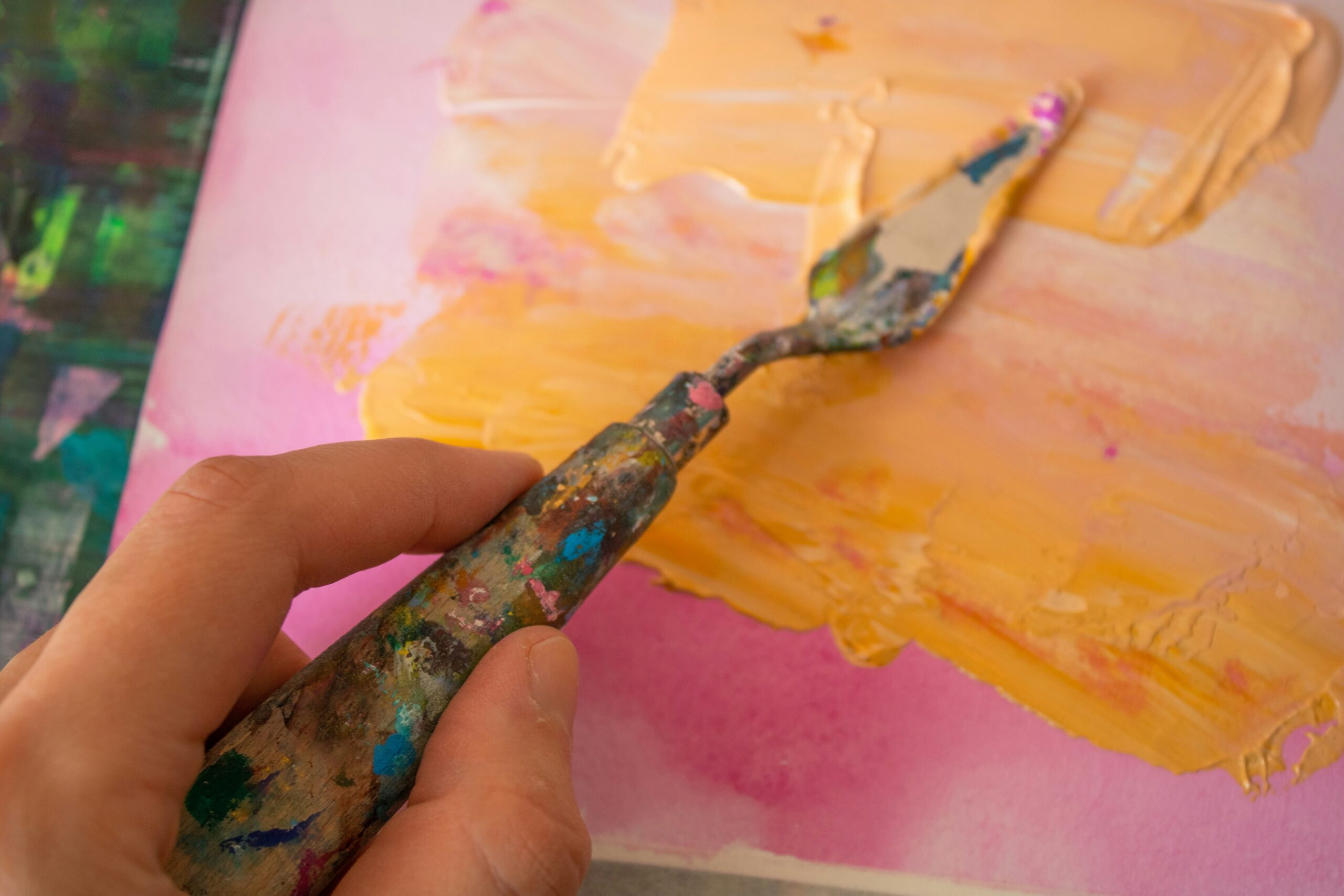 Close-up of a left hand hoding an artist's palette knife on a can