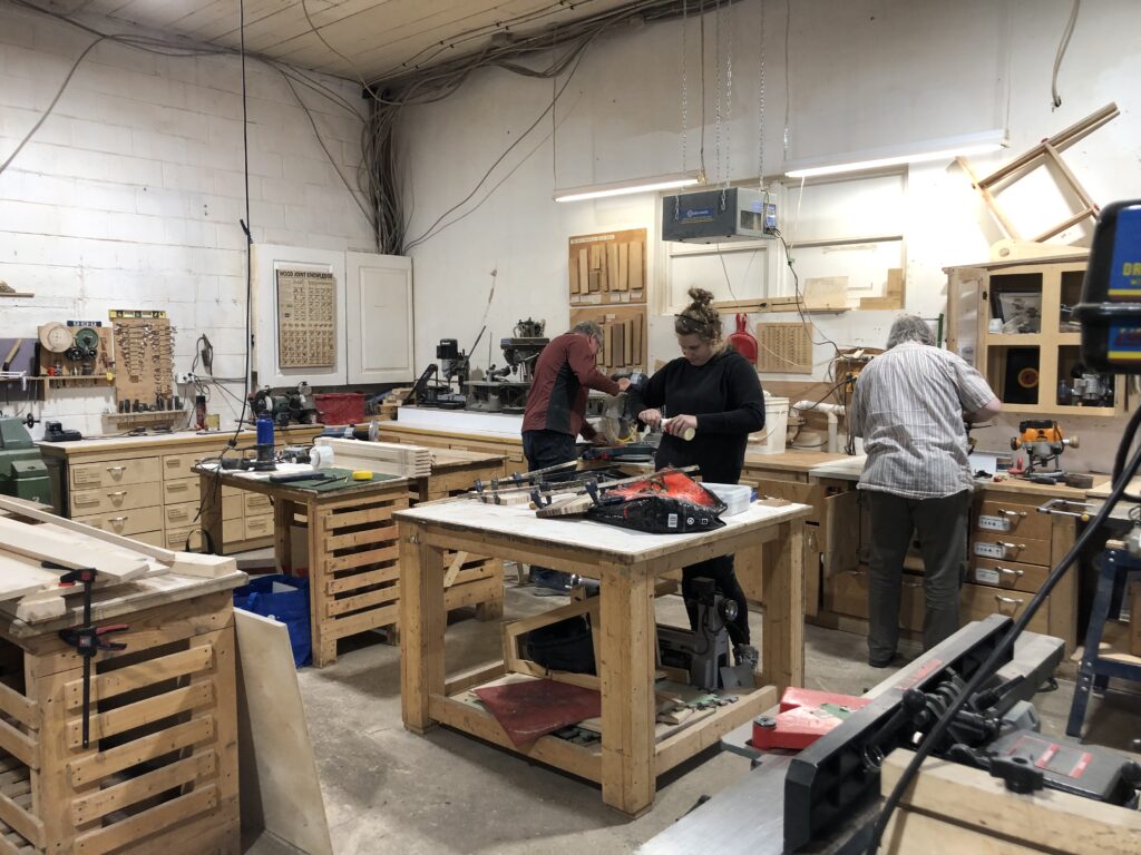 Three people working in a wood shop.