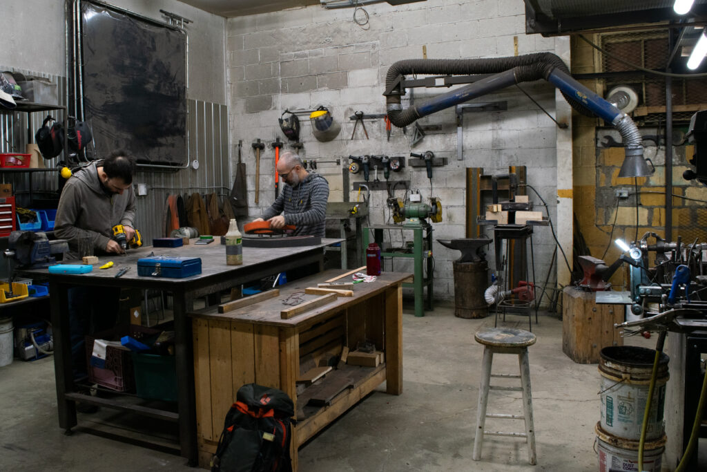 Two people work in a metal workshop.